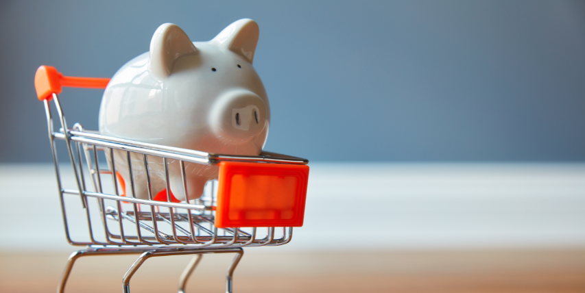 White piggy bank sitting in a small shopping cart.